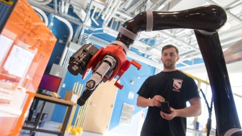 White male student works in an engineering lab on a robotic device.
