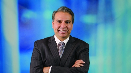 Headshot of white male wearing a suit and tie with his arms crossed.