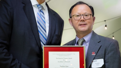 Two men pose with award certificate. Taller man on left presents the award.