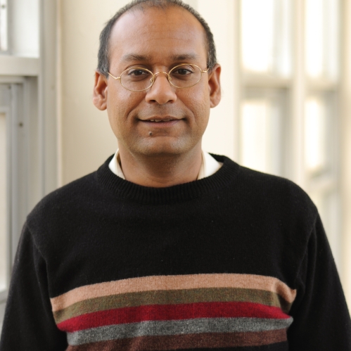 Head shot of male with eyeglasses and short hair, wearing a black pullover sweater.