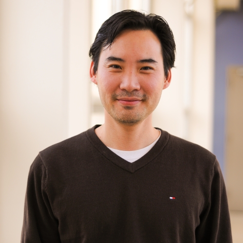 Head shot of Asian male wearing a dark brown pullover sweater.