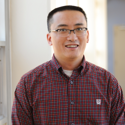 Head shot of Asian male with eyeglasses, wearing a maroon button down shirt.