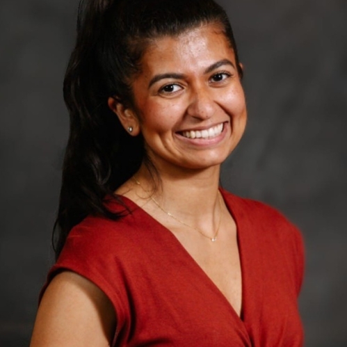 Woman smiling, her hair is in a ponytail, with red shirt