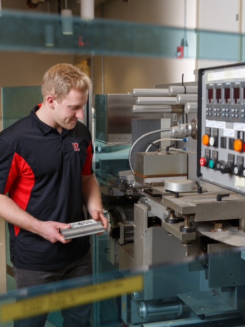 A male student works with industrial equipment that has controls and other mechanics.
