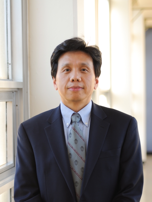 Head shot of Chinese male with short black hair, wearing a black suit, blue shirt, and patterned blue tie.