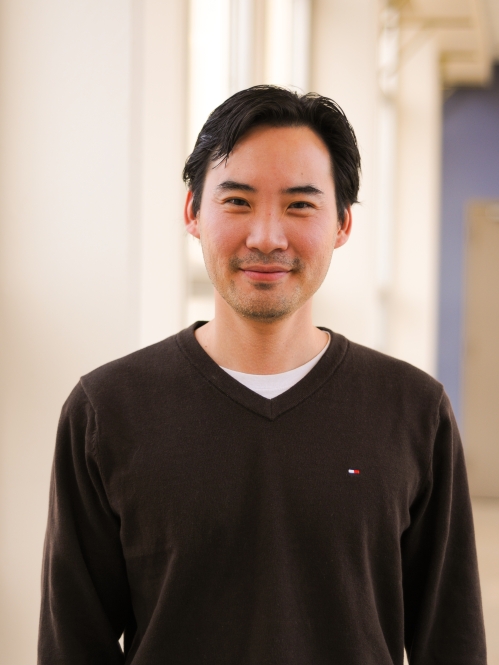 Head shot of Asian male wearing a dark brown pullover sweater.