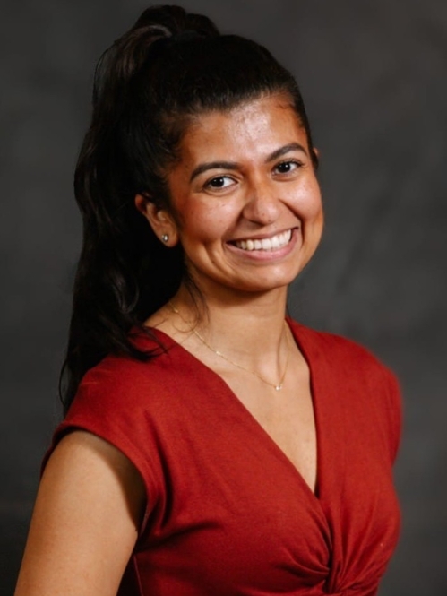 Woman smiling, her hair is in a ponytail, with red shirt