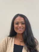 Head shot of woman with long black hair, wearing a beige sweater and a black shirt.