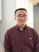 Head shot of Asian male with eyeglasses, wearing a maroon button down shirt.