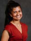 Woman smiling, her hair is in a ponytail, with red shirt