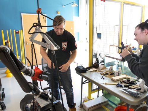 Male and female white students work in a lab with mechanical equipment.