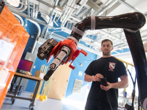 White male student works in an engineering lab on a robotic device.