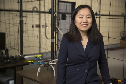 Female chinese woman in a drone lab with black hair wearing a black suit