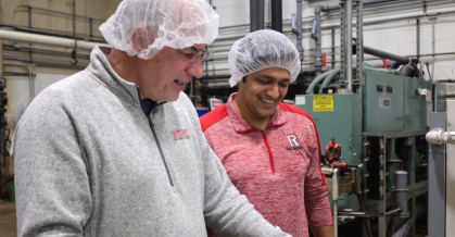 Two people wearing white hair nets standing in front of machinery 